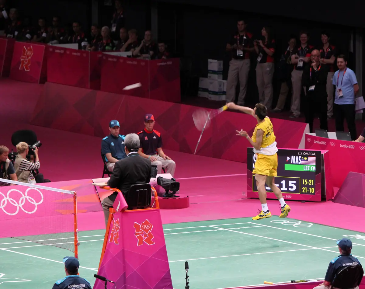 Un joueur en jaune renvoie un smash sur le court rose des Jeux olympiques de Londres.
